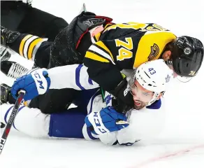  ?? ADAM GLANZMAN / GETTY IMAGES ?? Boston’s Jake Debrusk lands a punch on a pinned Maple Leafs’
Nazem Kadri in Saturday’s game in Boston.