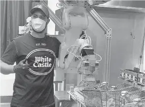  ?? MISO ROBOTICS ?? A White Castle employee shares a kitichen with a robot made by Miso Robotics that is capable of cooking French fries.