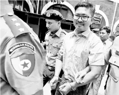  ?? — Reuters photos ?? Detained journalist Wa Lone walks escorted by police during a break at a court hearing in Yangon.