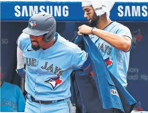  ?? GERRY ANGUS GETTY IMAGES ?? Blue Jay Lourdes Gurriel Jr. helps teammate Marcus Semien slip into the home run jacket after launching his 30th of the season in the eighth inning against the Tigers at the Rogers Centre.