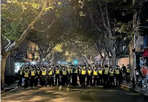  ?? AP ?? Chinese police officers block off access to a site where protesters had gathered in Shanghai.