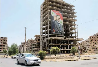  ?? /Reuters ?? High and mighty: Vehicles pass near a poster depicting Syria’s President Bashar alAssad in Douma, Syria.