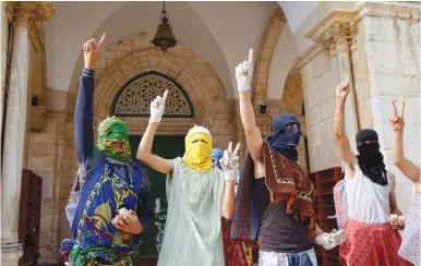  ?? (Reuters) ?? DON’T IGNORE them. Masked Palestinia­ns hold stones as they gesture during clashes with Israeli police during Ramadan near the Aksa Mosque in Jerusalem.