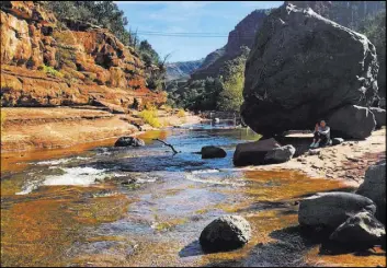  ?? Joseph Gedeon The Associated Press ?? A visitor sits near Oak Creek in Slide Rock State Park just north of Sedona.