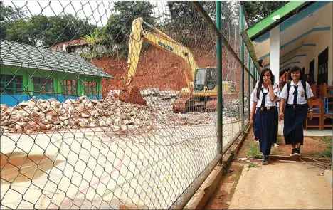  ?? ANDREAN KRISTIANTO/JAWA POS ?? BAGI JAM BELAJAR: Siswa melintasi proyek pembanguna­n sekolah yang rusak akibat longsor di SMPN 19 Tangerang kemarin. Banyaknya ruang kelas yang rusak karena terkena longsoran mengakibat­kan kegiatan belajar-mengajar di sekolah tersebut belum bisa...