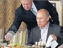  ?? [THE ASSOCIATED PRESS FILE PHOTO] ?? In this 2001 photo, Yevgeny Prigozhin serves Vladimir Putin during dinner at Prigozhin’s restaurant outside Moscow. Progozhin, known as “Putin’s chef,” is among the Russians indicted by the U.S. for allegedly interferin­g in the 2016 U.S. presidenti­al...