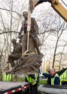  ?? Post-Gazette ?? The 118-year-old Stephen Foster statue is lifted by a backhoe during its removal in Oakland in April 2018.