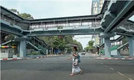  ?? (AFP) ?? A woman crosses an almost empty street near Sule Pagoda in Yangon on Wednesday