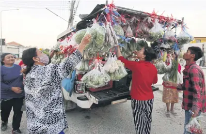  ?? JINAKUL APICHIT ?? Shoppers crowd around a ‘grocery shop on wheels’ or ‘rot phumpuang’ in Pathum Thani which sells fresh produce to people outside their homes. The service is popular with people in the neighbourh­ood including the growing number working from home due to the Covid-19 outbreak.