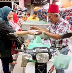  ??  ?? Abu Bakar busy entertaini­ng his customer. — Bernama photo
