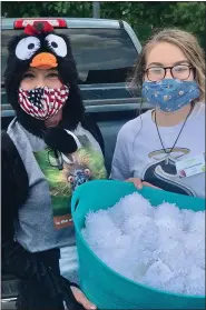  ??  ?? Cheryl Anderson, dressed as a penguin, and Christina Orlando, holding the “snowballs,” before the “snowball” fight.