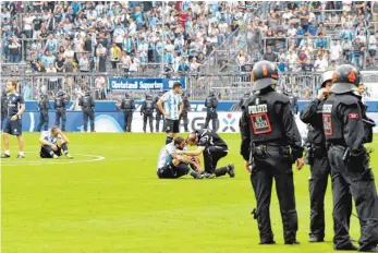  ?? FOTO: DPA ?? Spieler am Boden, von Polizisten beschützt: 1860 München nach dem Abstieg.