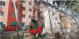  ?? ASYRAF RASID/THESUN ?? TIGHT PROCEDURES ... A soldier setting up a barbed wire barricade at the Bandar Bukit Tinggi 1 Apartments in Klang yesterday after the complex was put under an enhanced movement control order. –