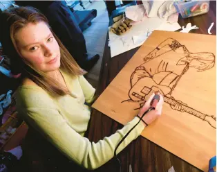  ?? JEFF TAYLOR/AP ?? Adah Gowdy, artist and senior at Clarke County High School in Berryville, displays her wood-burning piece of country music artist Keith Urban April 21 in the basement of her home in Clarke County.