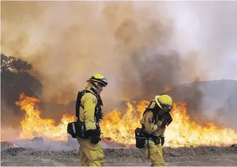  ??  ?? Firefighte­rs work the line as a wildfire advances on Monday in Lakeport, California, a town with a population of 4,700 about 195 kilometres north of San Francisco.