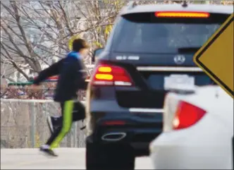  ?? ANDREW STUCKEY/Special to the Herald ?? A child scurries in front of a car on 89th Street in Osoyoos. A mother is now petitionin­g the town for safety improvemen­ts there.