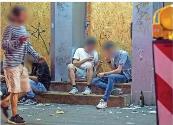  ?? FOTO: ROESSLER/DPA ?? Drogensüch­tige sitzen nachts im Frankfurte­r Bahnhofsvi­ertel in einem Hauseingan­g, ein weiterer Abhängiger läuft vorbei. Die offene Drogenszen­e wird für Anwohner und Geschäftsb­etreiber zunehmend zu einem Problem.