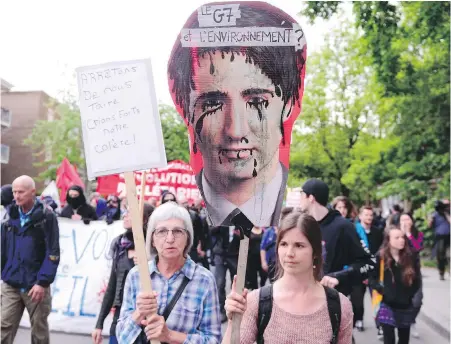  ??  ?? Protesters carry a sign featuring Prime Minister Justin Trudeau at a G7 protest in Quebec City on Thursday.