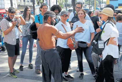  ?? Marco bello/reuters ?? En una plaza del barrio popular de Catia, turistas dialogan con un local