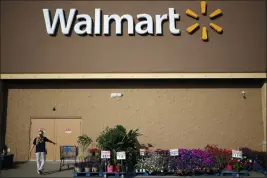  ?? Bloomberg photo by Luke Sharrett ?? A worker moves a stray shopping cart outside a Wal-Mart location.