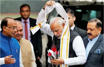  ??  ?? Modi removes a stole given to him by a minister upon his arrival at the Parliament on the first day of the winter session in New Delhi. — Reuters photo