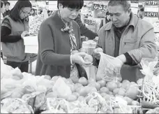  ?? WANG JIANKANG / FOR CHINA DAILY ?? Customers put tomatoes into a plastic bag at a supermarke­t in Suzhou, Jiangsu province.