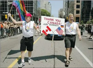  ?? — REUTERS FILES ?? Henry Pabian (left) and Jason Rawls of Ohio toast cheering crowds during the 2003 Pride Parade in Toronto after getting married.