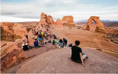  ??  ?? Visitors marvel at Delicate Arch. Writer Edward Abbey once wrote that the desert area “lies beyond the end of the roads.” Now, 4,000 visitors amount to a slow day at Utah’s Arches.