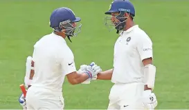  ??  ?? India’s Ajinkya Rahane (left) is congratula­ted by Cheteshwar Pujara on reaching his half-century on Sunday