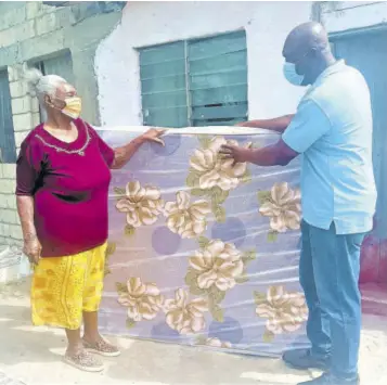  ??  ?? Cherry Thompson from Gravel Hill, Clarendon, collects her mattress from Senior Community Relations Officer Phillip Biggs of Jamalco.
