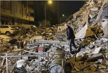  ?? DEPO PHOTOS VIA AP ?? A man searches collapsed buildings in Diyarbakir, southern Turkey, Feb. 6, 2023. A powerful earthquake has caused significan­t damage in southeast Turkey and Syria and many casualties are feared. Damage was reported across several Turkish provinces, and rescue teams were being sent from around the country.