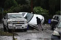  ?? AP PHOTO ?? DAMAGED IN DELUGE
A woman examines cars damaged by floods after a storm in San Diego, California, on Monday, Jan. 22, 2024.