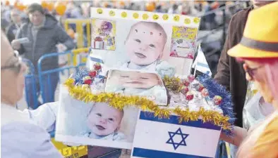  ?? ABIR SULTAN / EFE ?? Homenaje Varios israelís sostienen un pastel de cumpleaños con fotos del pequeño Kfir Bibas, ayer en Tel Aviv. -