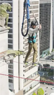  ??  ?? Ryan LaChappell­e — partnered with buddy Kenneth McAlpin — navigates a tightrope walk between two roofs at the Fairmont Hotel in Vancouver.