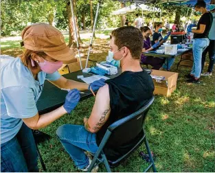  ?? STEVE SCHAEFER FOR THE ATLANTA JOURNAL-CONSTITUTI­ON ?? Emory University physician assistant student Nicole Groff (left) administer­s a COVID-19 vaccine shot to Gage Kirby during the Atlanta Jazz Festival on Sunday in Piedmont Park. The vaccinatio­ns were coordinate­d by Emory’s outbreak response team.