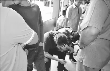  ??  ?? The two accused (seated) lowering their heads to prevent press photograph­ers from taking their photos at Sibu Courthouse yesterday.