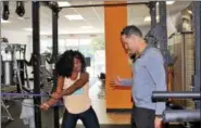  ?? MICHILEA PATTERSON — DIGITAL FIRST MEDIA ?? Ernie Groff, owner of I Am Fit Studios, helps client Fabienne Daniel work on her arm strength with exercise bands at the Sinking Spring location.