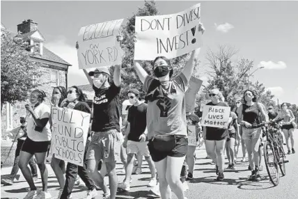  ?? AMY DAVIS/BALTIMORE SUN PHOTOS ?? Uma Scharf, front, and others march from Cold Spring Lane to Belvedere Square to highlight the segregatio­n symbolized by York Road.