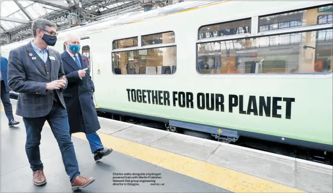  ?? PHOTOS / AP ?? Charles walks alongside a hydrogen powered train with Martin Frobisher, Network Rail group engineerin­g director in Glasgow.