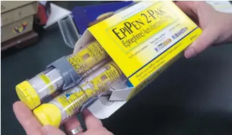  ?? RICH PEDRONCELL­I, THE ASSOCIATED PRESS ?? A pharmacist holds a package of EpiPen epinephrin­e auto-injectors in Sacramento, California.