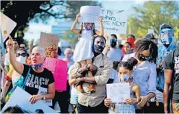  ?? MIKE STOCKER/ SOUTH FLORIDA SUN SENTINEL ?? Donavan Jackson, holding his daughter, Naomi Jacokson, 4, along with daughter Genesis Brown, 7, and their mom Chimene Purdy during a protest in Coral Gables last year. The demands of protesters in Florida this summer for police reform may finally be met with a recently submitted House Committee bill.