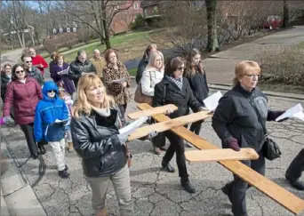  ?? Emily Matthews/Post-Gazette ?? Members of St. Gregory Byzantine Catholic Church carry a wooden cross down Brookdale Drive in Upper St. Clair on Sunday. The Byzantine Catholic Church honors the cross on the third Sunday of Lent and Father Valerian M. Michlik said they especially wanted to carry the cross this week to spread Christ’s love and compassion in their community. For a video, visit post-gazette.com.