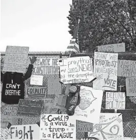  ?? TASOS KATOPODIS/GETTY ?? Signs calling to “defund the police” join others on a steel fence at Lafayette Park near the White House in Washington, D.C.