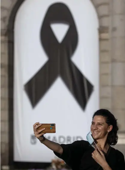  ?? FOTO: MANU FERNANDEZ/TT–AP ?? En kvinna tar en selfie på Puerta de Alcala i Madrid framför minnesmärk­et över dem som gått bort i covid-19. Krismedvet­enheten vilar över Spanien då restriktio­nerna ska luckas upp.