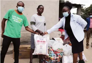  ?? — Picture Memory Mangombe ?? Zimpapers public relations manager Pauline Matanda (right) and Food W orld marketing manager Albert Nyadzayo (left) hand over groceries, money and kitchen utensils to Zincan security officer Taurai Alberto after her house went on fire in Epworth yesterday.