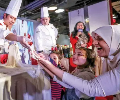  ?? TONG YU / FOR CHINA DAILY ?? Relatives of diplomats posted to China inspect extremely thin noodles made by Chinese chefs during a cooking competitio­n for diplomats and their families, in Tianjin on Dec 29. Diplomats from 11 countries and their relatives were invited to the 13th edition of the competitio­n.