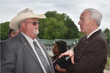  ?? Staff photo by Jim Williamson ?? ■ Arkansas Gov. Asa Hutchinson, right, talks to Hempstead County Sheriff James Singleton, left, about the plans for converting the Migrant Farm Labor Center in Hope to a juvenile detention behavioral center. Hutchinson described the plan as government...