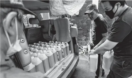  ?? REUTERS ?? Residents prepare containers of cooking oil to be distribute­d to locals at a filling station after stocks ran out in Jakarta, Indonesia, on March 10.