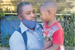  ?? ?? Jason Bryan Sr holds five-year-old son, Jeremiah, in Gutters, St James, on Tuesday. Eleven-year-old Jason Bryan Jr, the elder brother, was mowed down by a car on Mother’s Day in the community. He succumbed to his injuries at hospital on Monday.