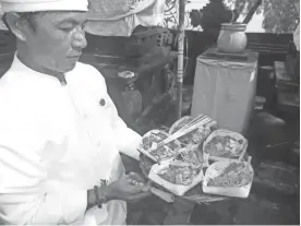  ??  ?? A Hindu priest presents an offering to the gods at Jimbaran Bay, Bali.